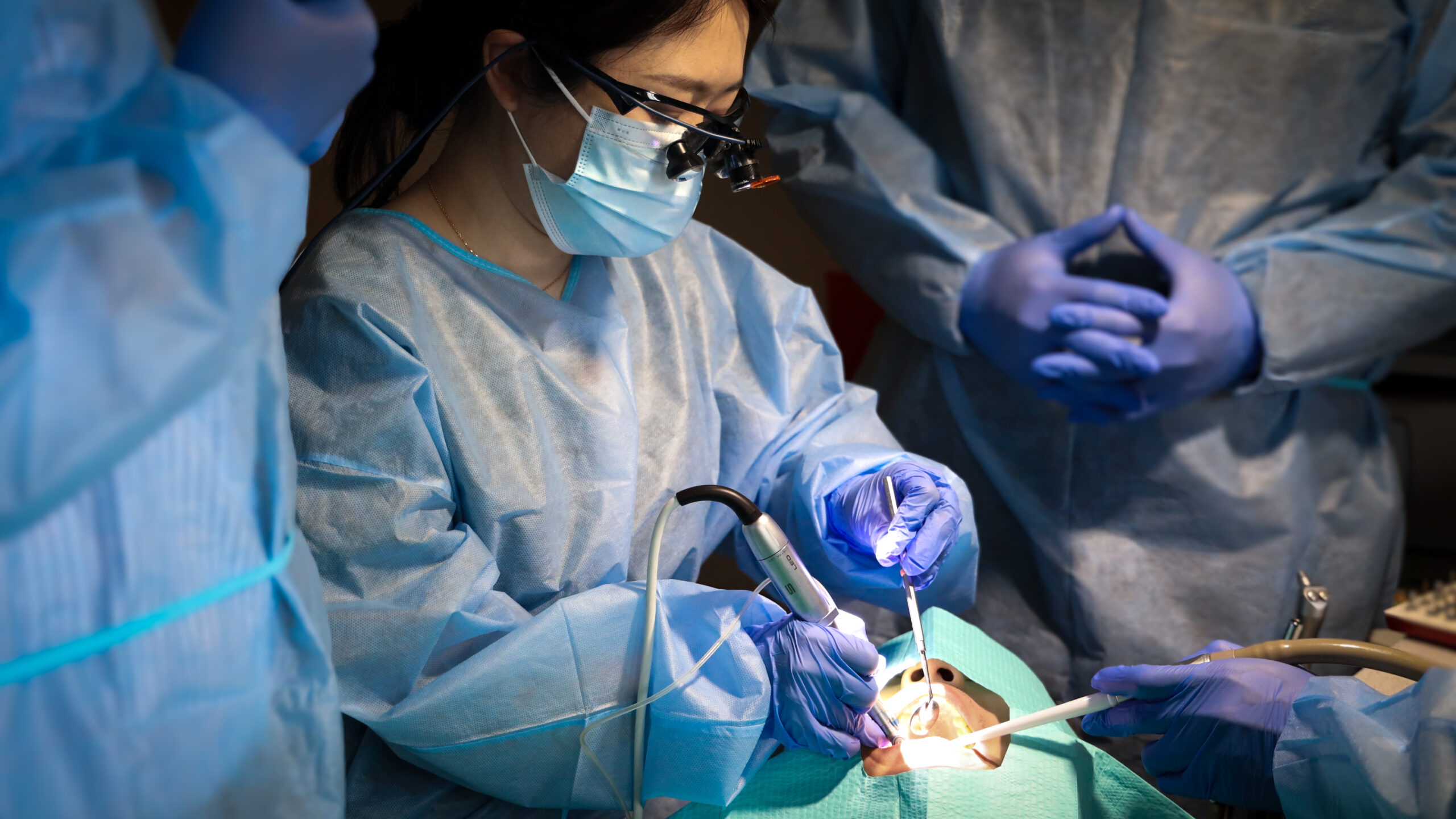 A dentist in loupes treating a patient during a Think Dental Institute clinical course