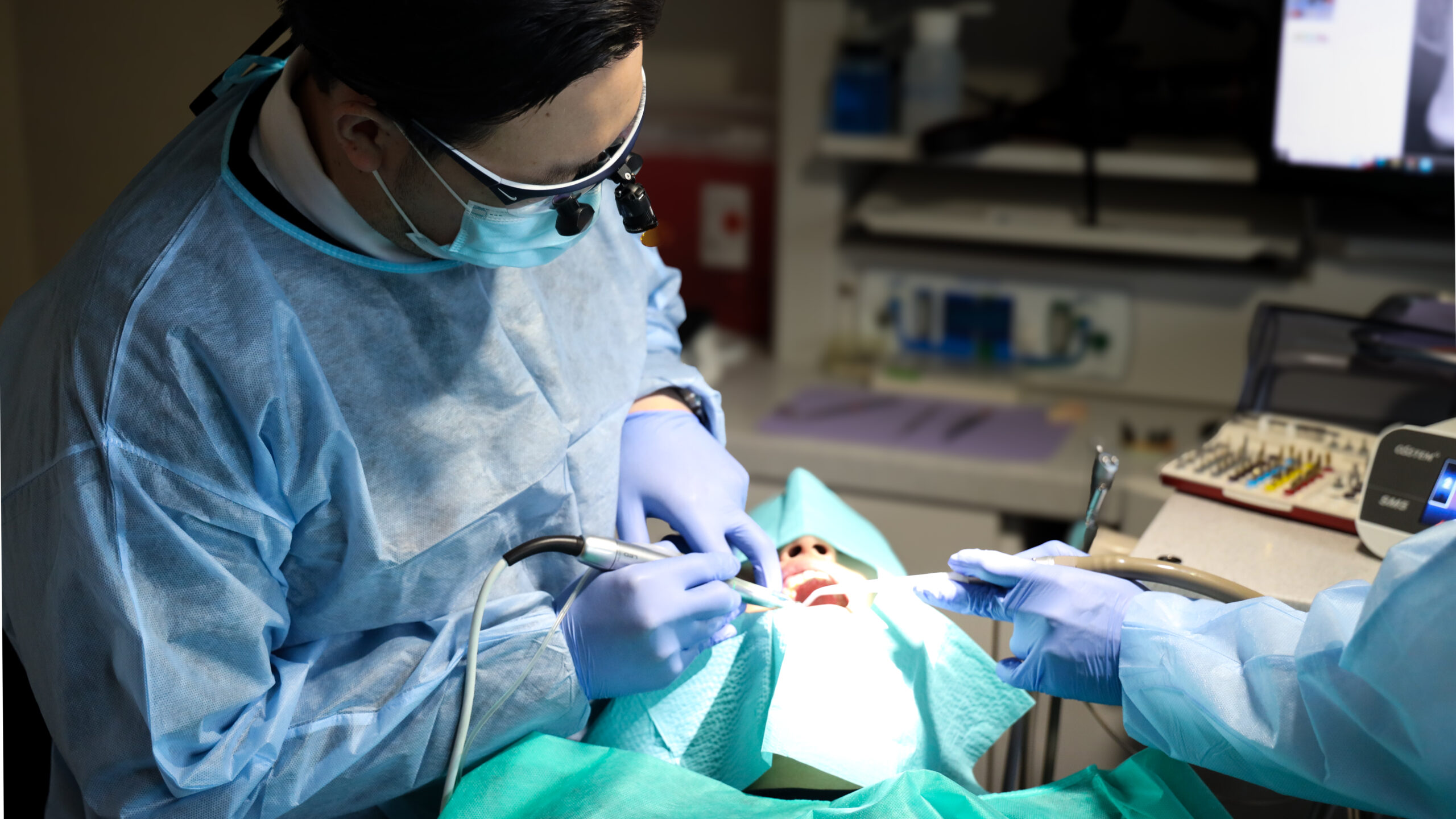 A dental assistant's gloved hands supporting a dentist during treatment